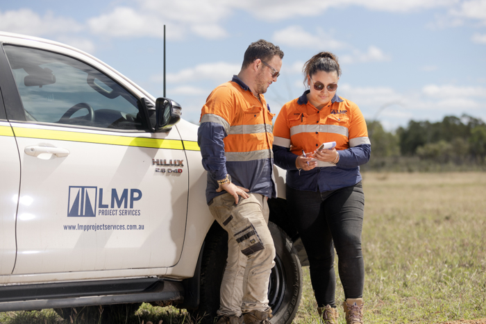Two LMP Project Services employees discussing plans next to a company vehicle. Two LMP Project Services employees discussing plans next to a company vehicle.